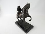 bronze statue of a man riding a horse on a marble base