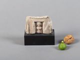 une figurine représentant une femme dans une vitrine et une noix posée sur un socle