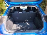the back of a blue car with its trunk open in a parking lot