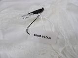 the label on a white dress is attached to a black and white tag