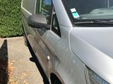 a silver van parked in a parking lot next to a hedge