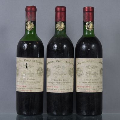three bottles of red wine sit on a glass table