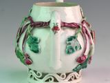 a white vase with green and pink decorations on it