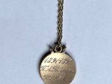 a close up of a gold necklace with a bird on it