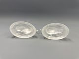une paire de boucles d'oreilles ovales en plastique transparent posées sur une surface grise