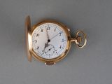 une montre de poche en or posée sur une surface grise