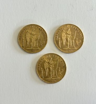 three gold coins sitting on top of a white surface next to each other