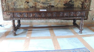 une table en bois avec un panneau devant une tapisserie
