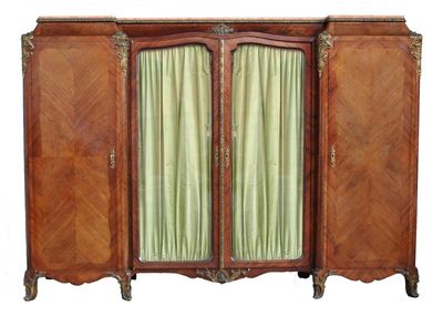 une armoire ancienne en bois à deux portes, ornée d'un rideau vert