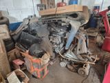 a pile of junk in a garage with a car in the background