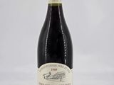 a bottle of red wine sitting on top of a white table