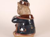 a ceramic sculpture of a bear sitting on a chair