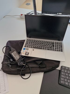 un ordinateur portable posé sur un sac, à côté d'un clavier
