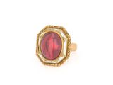 gros plan d'une bague en or avec une pierre rouge