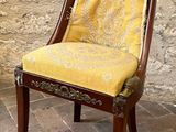 a chair with a yellow upholstered seat in front of a stone wall