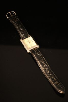 a close up of a watch on a black surface with a black background