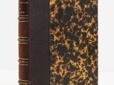 un vieux livre posé sur une table blanche à côté d'un mur blanc