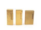 three gold lighters sitting side by side on a white surface