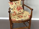 une chaise en bois avec un coussin posé dessus, dans une pièce