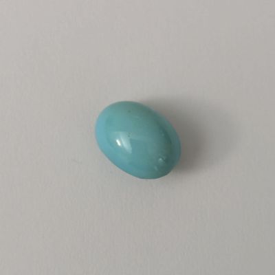un gros plan d'une pierre ovale bleue posée sur une surface blanche