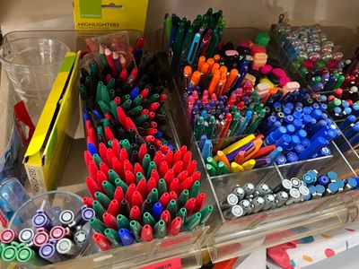 many different colored pens and markers in a clear container