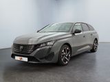 Une voiture grise est garée dans une grande pièce au sol noir.