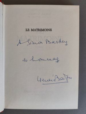 un livre ouvert, sur lequel figure un titre écrit à la main, posé sur une table