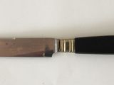 a close up of a knife on a white surface with a black handle