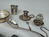a table with silver objects on it including a bowl, spoon, salt shaker, and other items