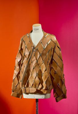 brown leather jacket on a mannequin stand against a red wall