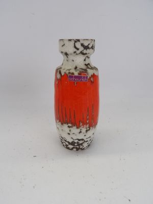 un vase rouge et blanc posé sur une surface blanche