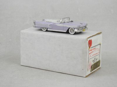 une petite voiture posée sur une boîte, sur une surface blanche