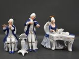 three figurines of people playing musical instruments in front of a table