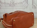 brown leather handbag on a wooden table in front of a wall
