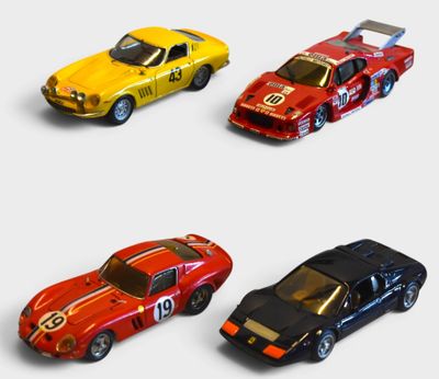 four toy cars are lined up in a row on a white surface
