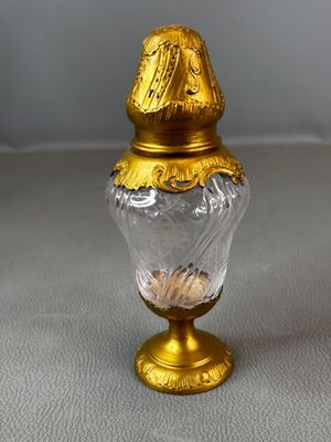 gold and clear glass vase with a gold lid on a white surface
