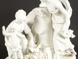 une figurine blanche représentant une femme et deux enfants avec un panier de fleurs