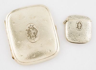 two pieces of silver jewelry sitting on top of a white surface