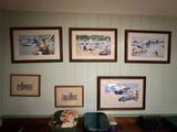 many pictures hanging on the wall above a suitcase