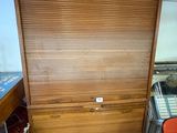 a wooden cabinet in the corner of a room next to a desk