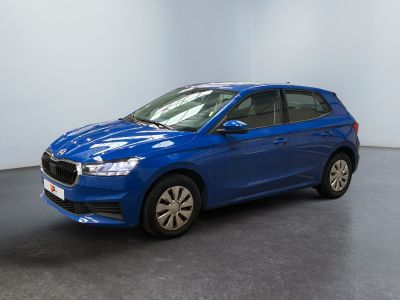 Une voiture bleue est garée dans une pièce aux murs blancs.
