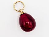 un gros plan d'un pendentif rouge en forme de larme sur une surface blanche