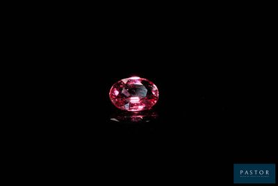 a close up of a pink diamond on a black surface