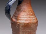 a brown and blue vase with a handle on it