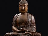 une statue en bois représentant un Bouddha assis sur un fond noir