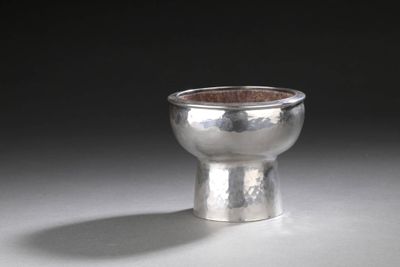 une coupe en argent posée sur une table, sur fond noir
