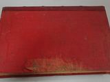 an old red book sitting on top of a white table