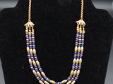 un collier de perles dorées et bleues sur un mannequin d'exposition