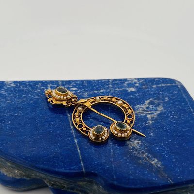 a close up of a blue stone with a gold broochle