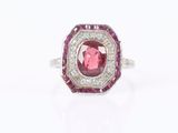 a close up of a pink and white diamond ring on a white surface